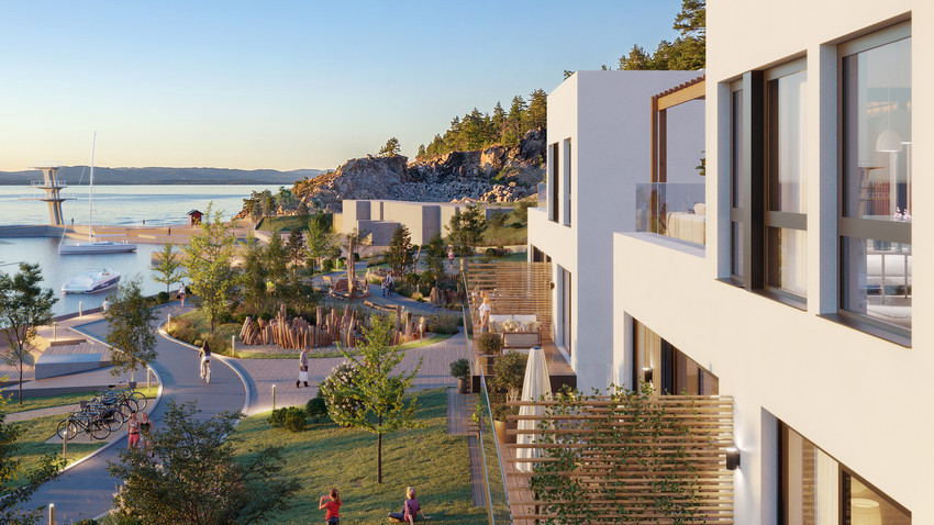 Boligområde ved fjorden med lave bygg med grønne oppholdssoner og badebrygge og hoppetårn.