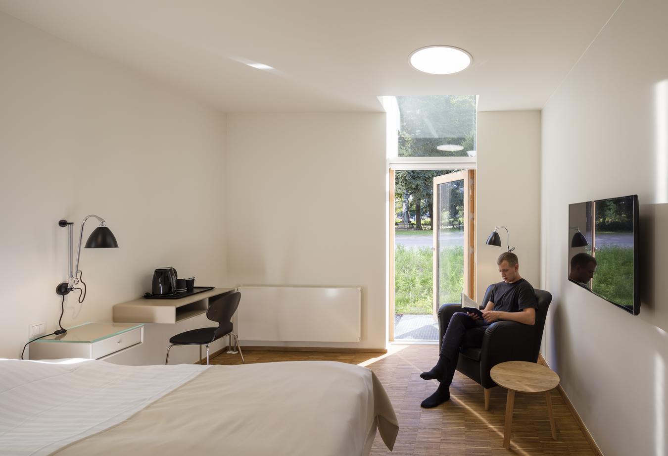 Person sitting and reading book by patio door in patient room. Photo