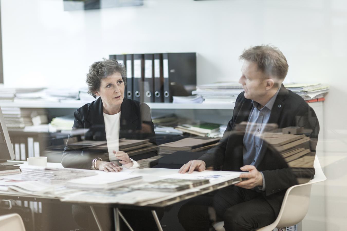 Two people talking together around a table. Photo