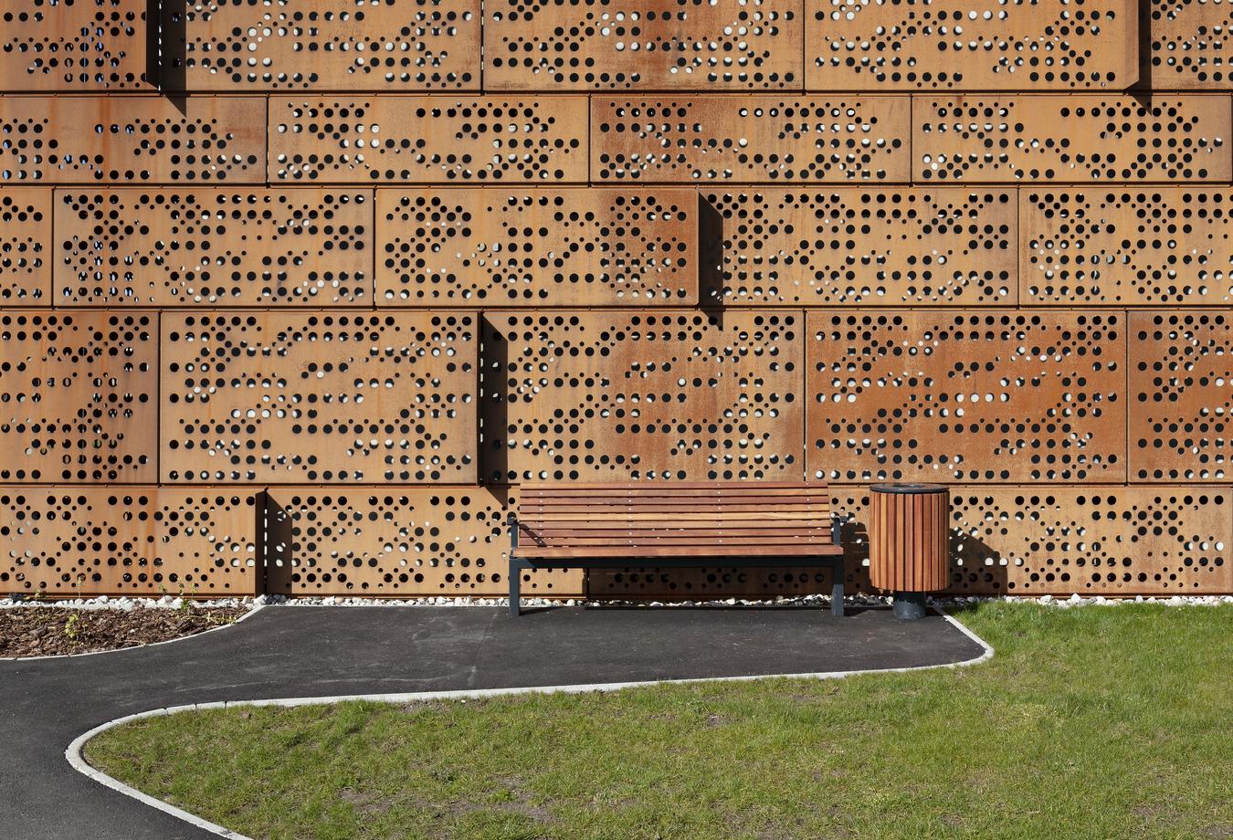 Bench in front of corten steel façade. Photo