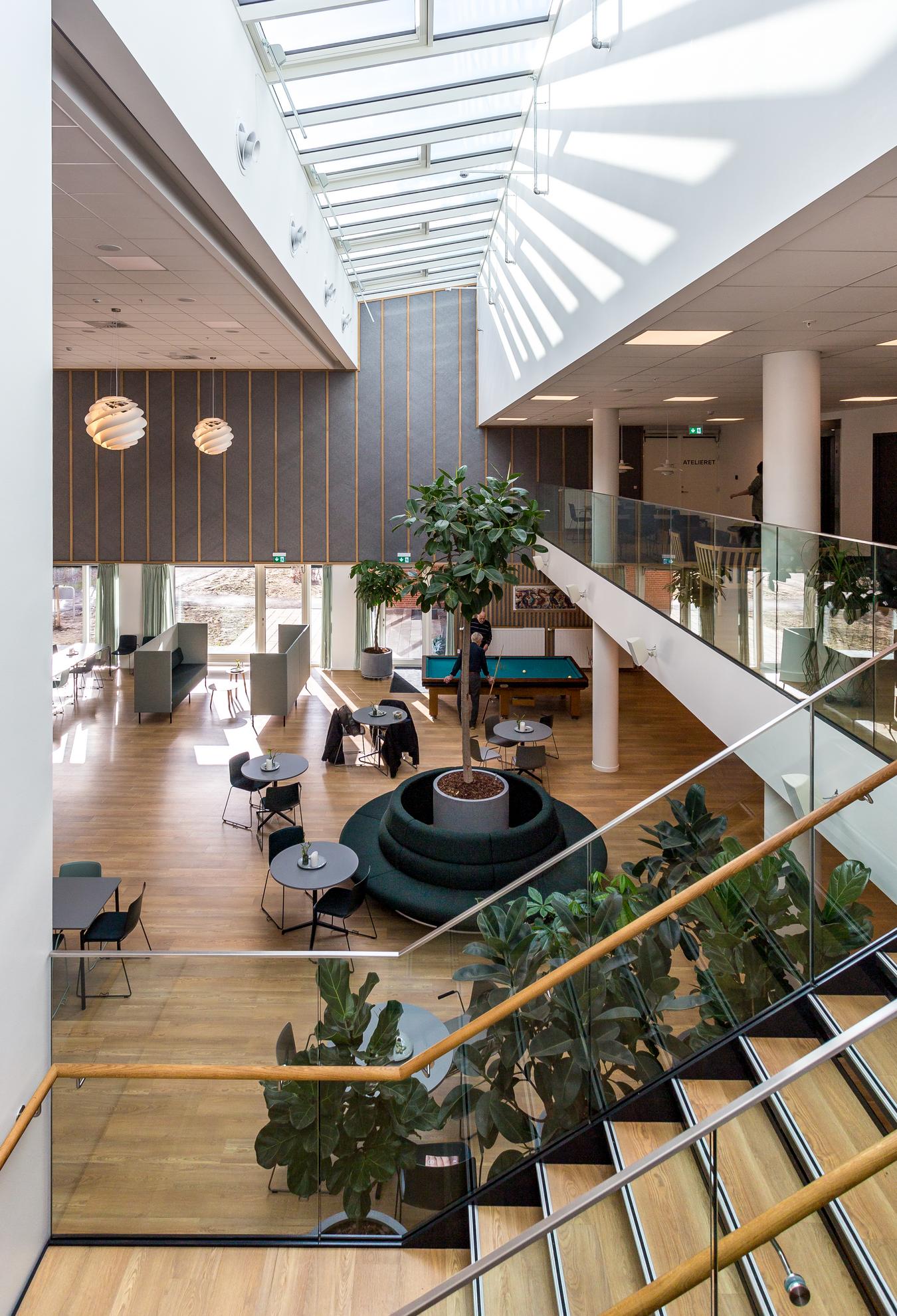 Indoor common area with pool table, seating areas and plants. Photo