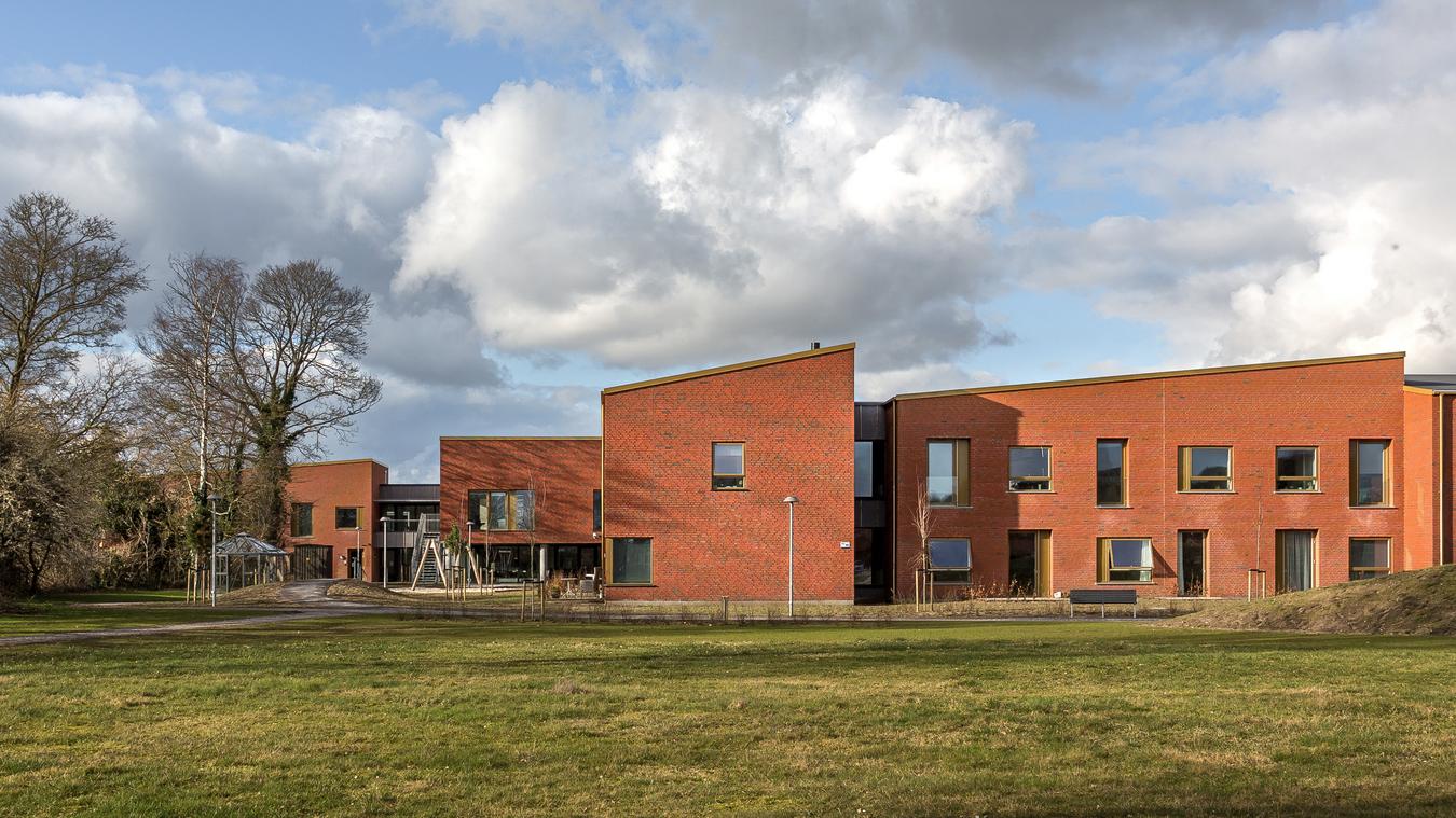 Red brick house with green area in front. Photo