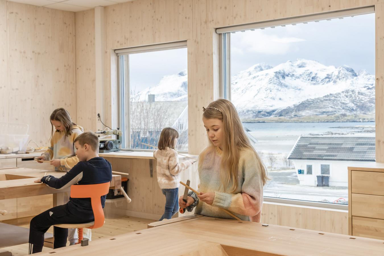 Elever i aktivitet i klasserommet. Utsikt mot landskap gjennom store vindusflater. Foto 