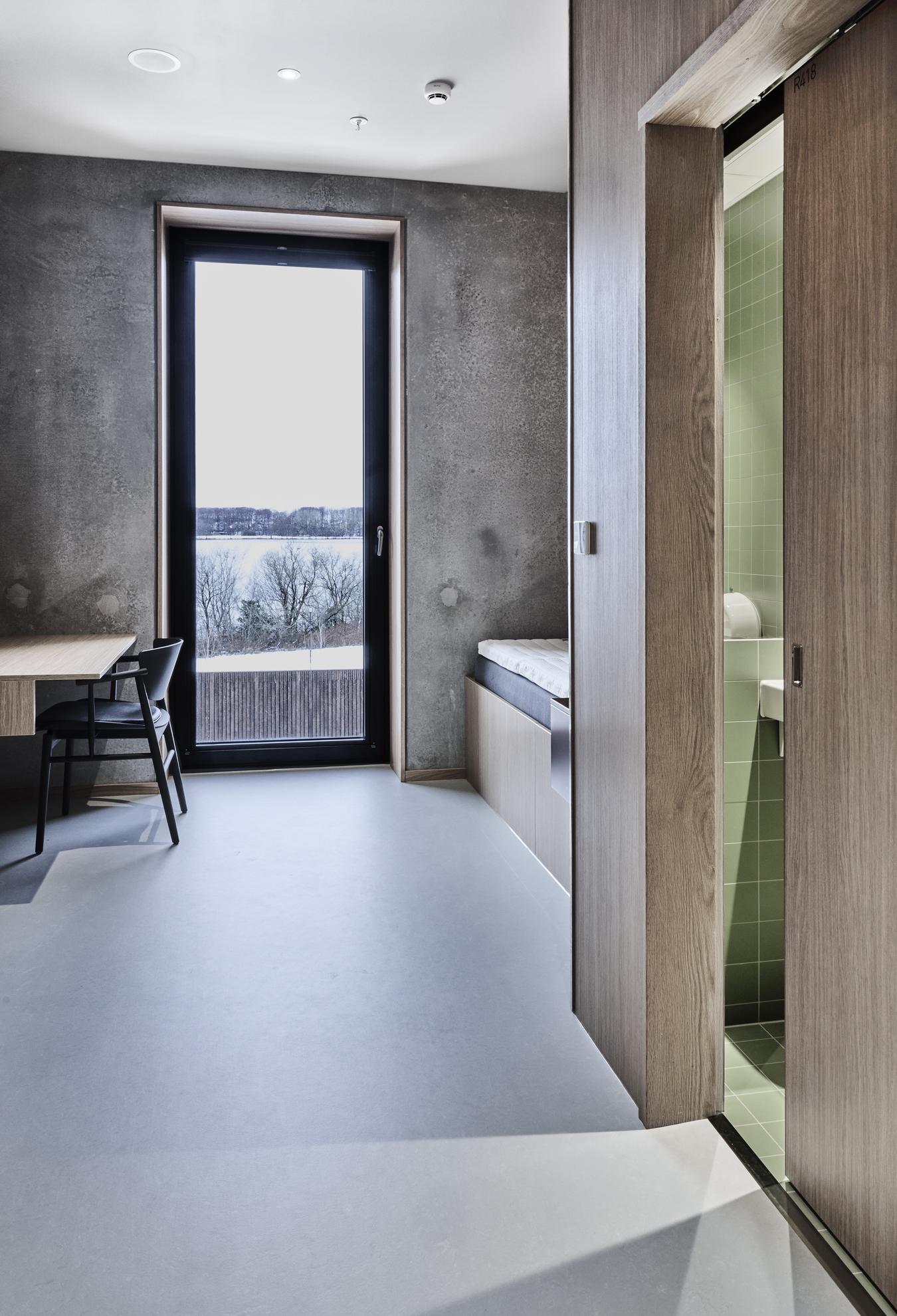 Bedroom and bathroom with interior in concrete, wood and green tiles. Photo