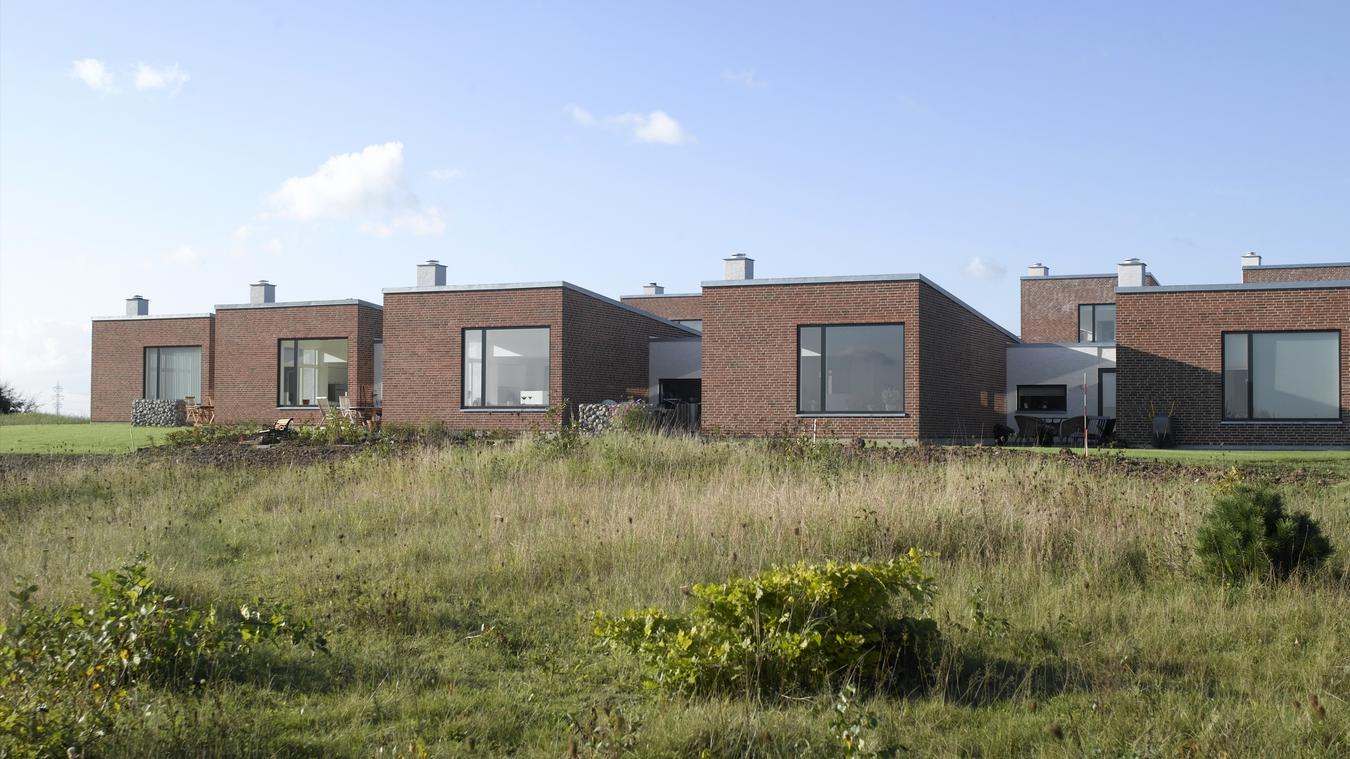 Small brick buildings in green terrain. Photo